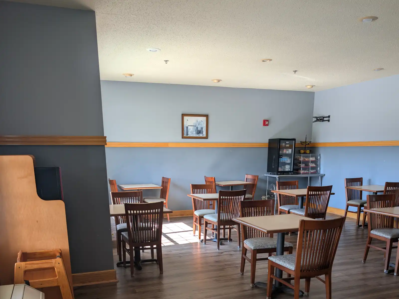 The breakfast dining room at Chisholm Inn & Suites, with tables beside the windows