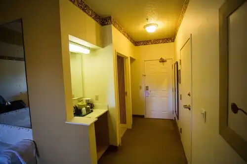The entry of a guest room at Chisholm Inn & Suites, with the coffee maker and vanity nook